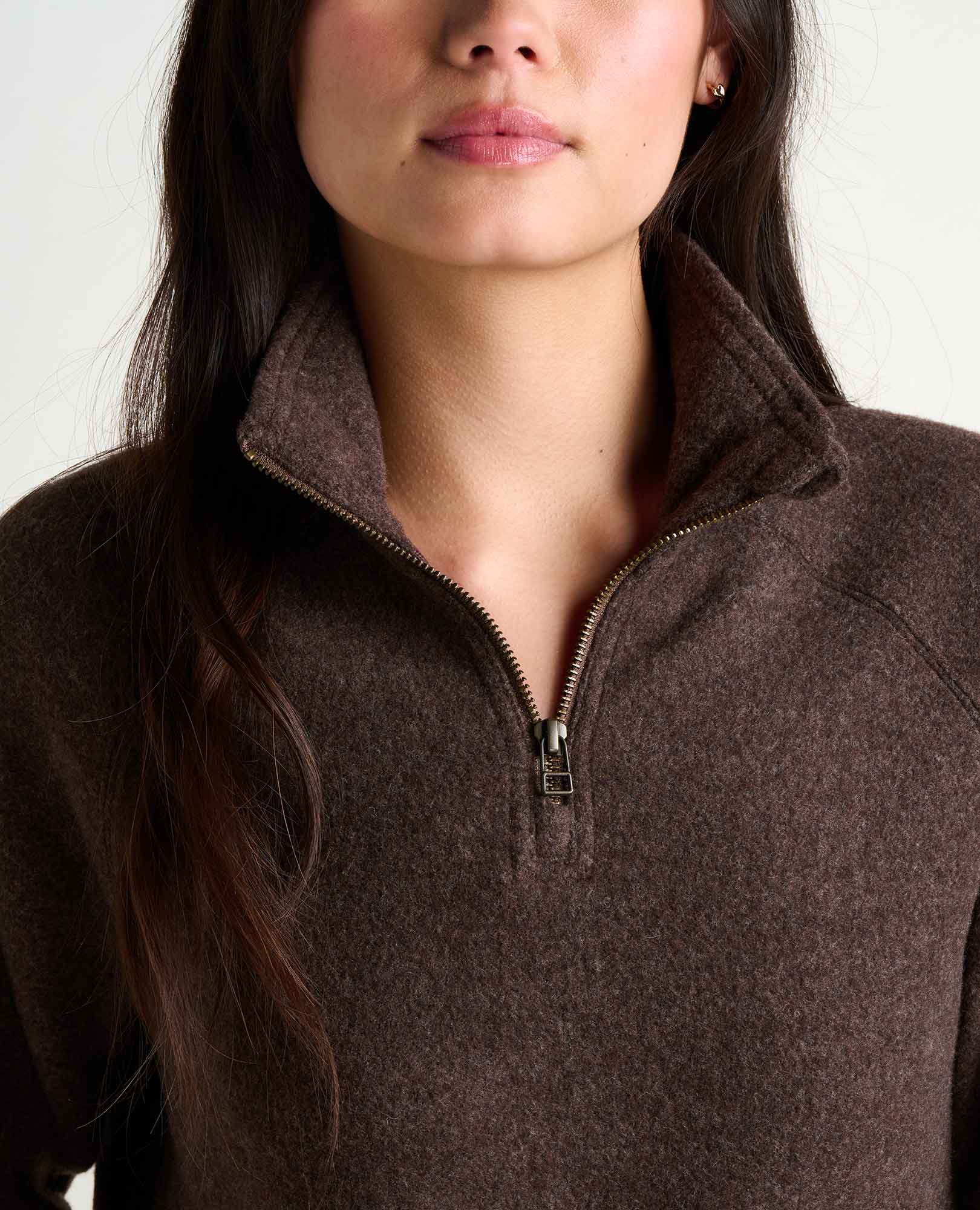 Close-up detail of women's quarter-zip fleece pullover with gold zipper and funnel collar
