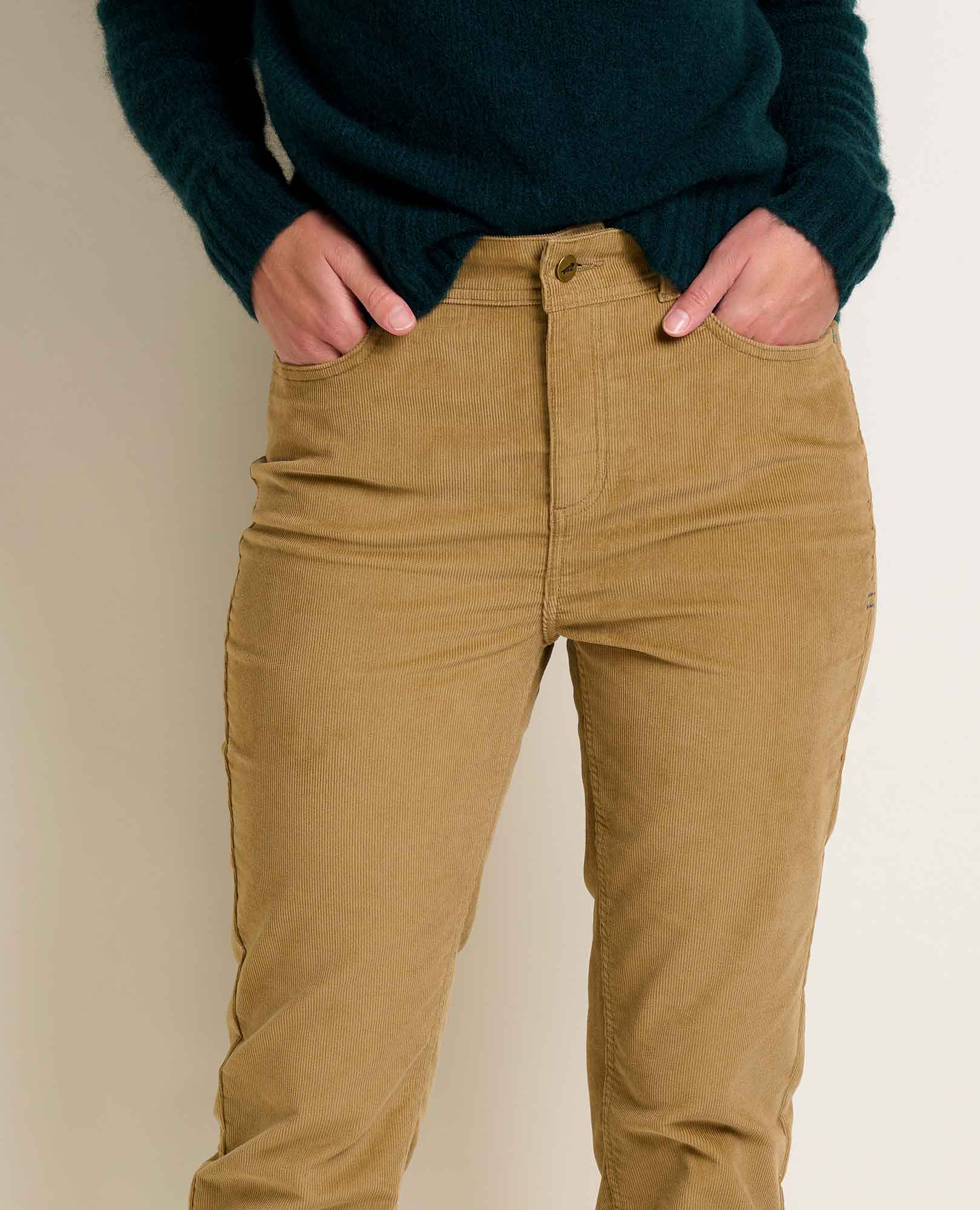 Women's slim-fit corduroy pants in warm tan, front close-up view showing waistband and pockets