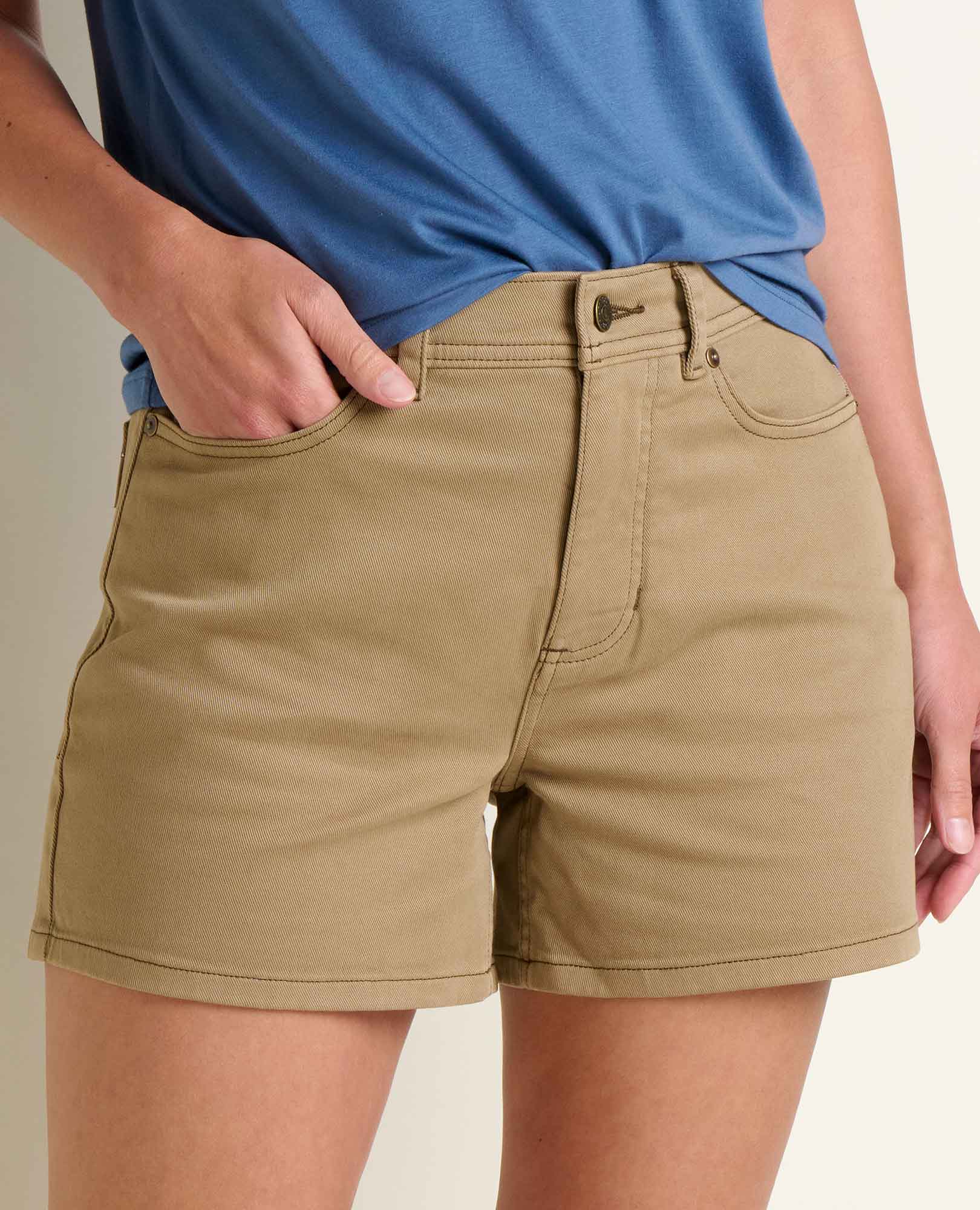 Tan colored women's denim shorts with rolled cuffs and front pockets, lifestyle view