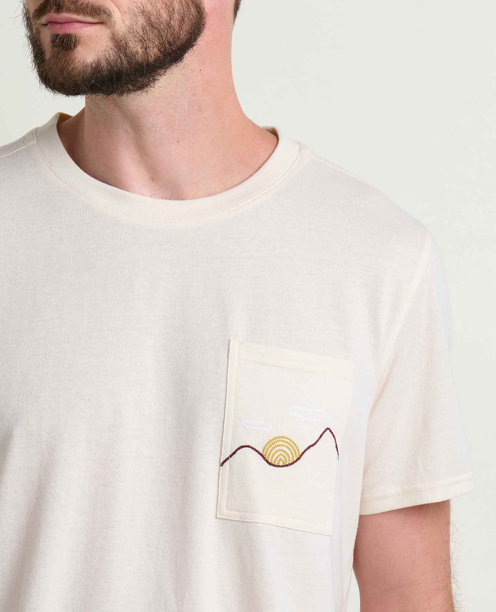 Light colored crew neck t-shirt with embroidered sun and wave design on chest pocket