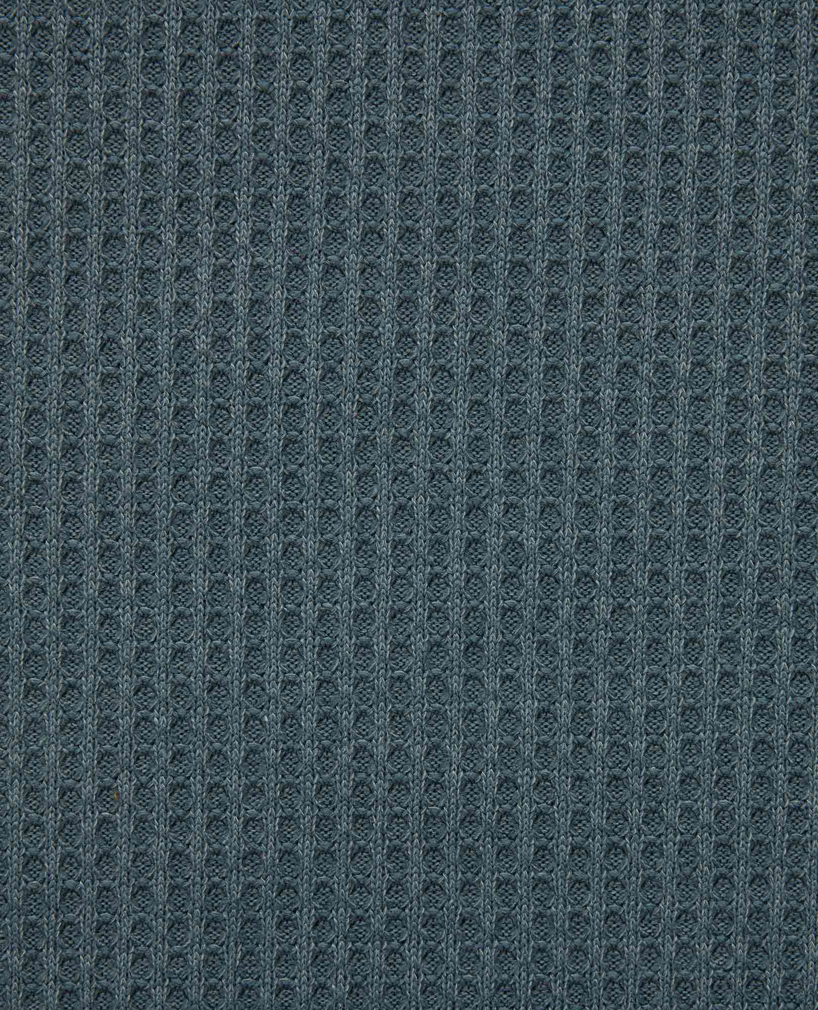 Close-up detail of dark blue waffle-knit fabric texture showing ribbed pattern