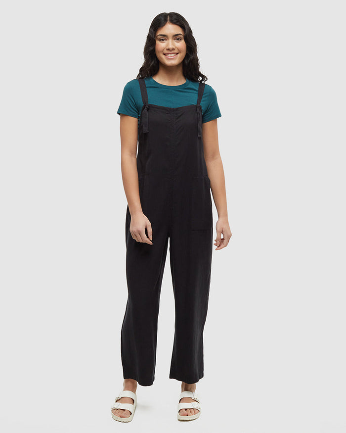 Black adjustable strap jumpsuit with wide leg pants worn over teal t-shirt