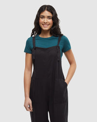 Black jumpsuit with adjustable straps and front pockets, worn over teal shirt