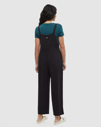 Black jumpsuit with adjustable straps worn over teal t-shirt, back view