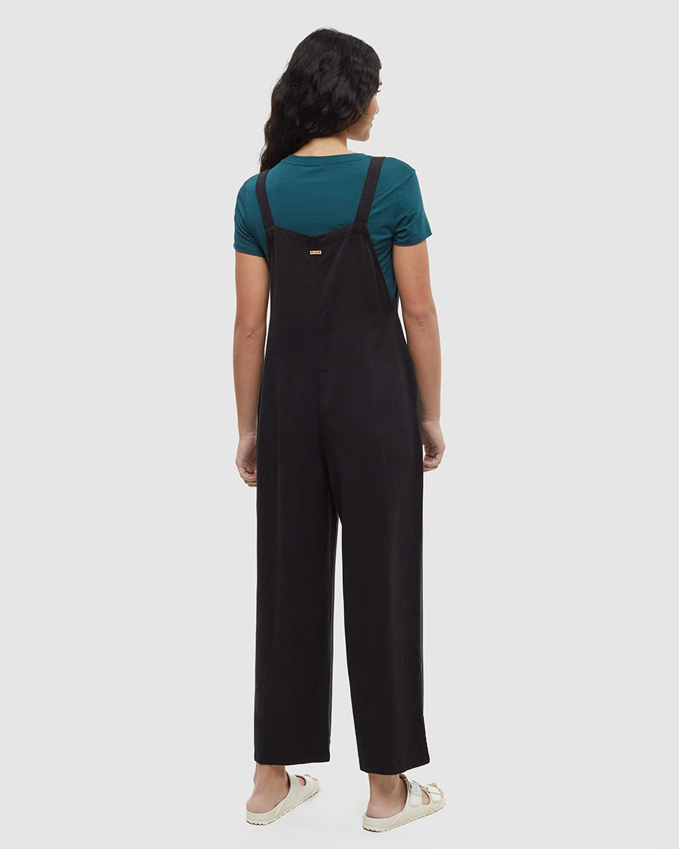 Black jumpsuit with adjustable straps worn over teal t-shirt, back view