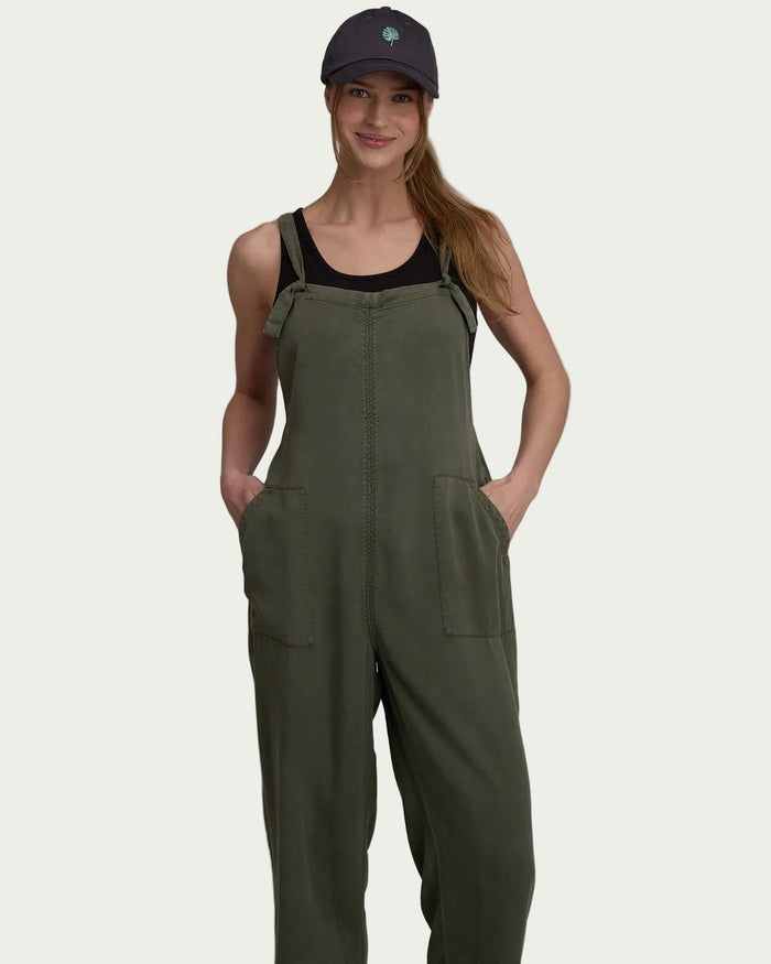 Olive green jumpsuit with adjustable straps and front pockets worn by woman with baseball cap