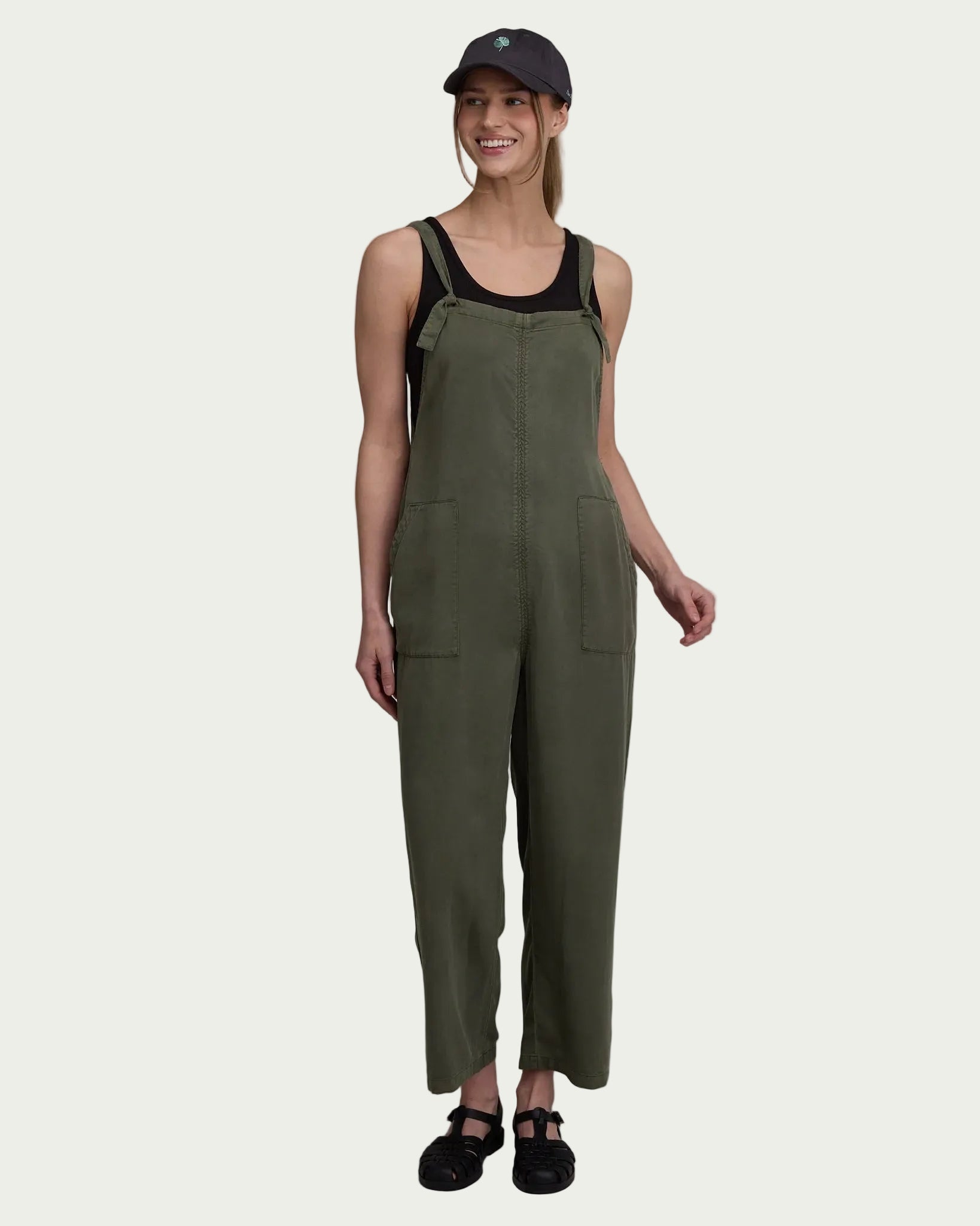 Olive green sleeveless jumpsuit with adjustable straps and front pockets on model