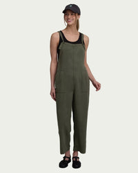 Olive green sleeveless jumpsuit with adjustable straps and front pockets on model