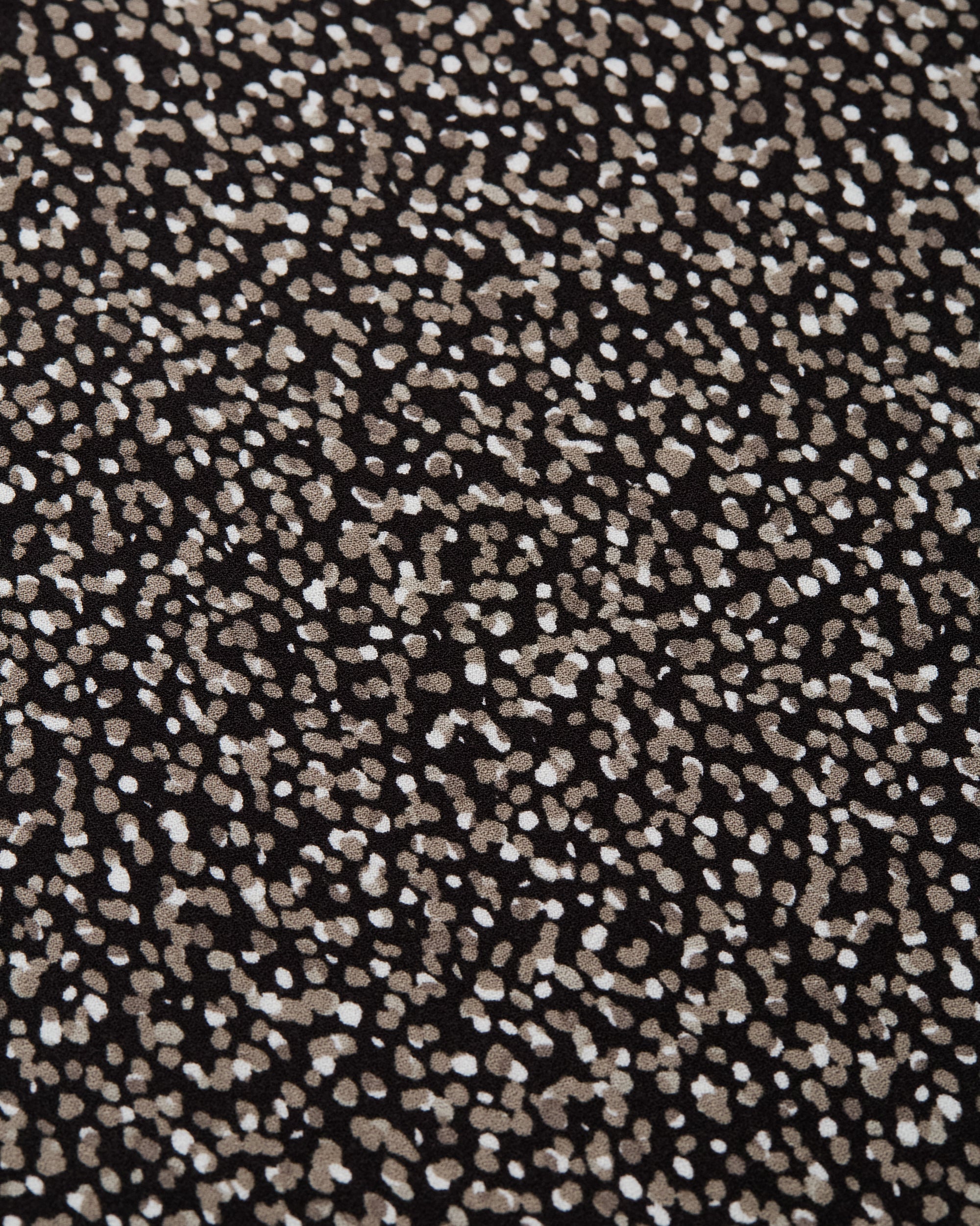 Black fabric with scattered white and beige polka dot pattern detail