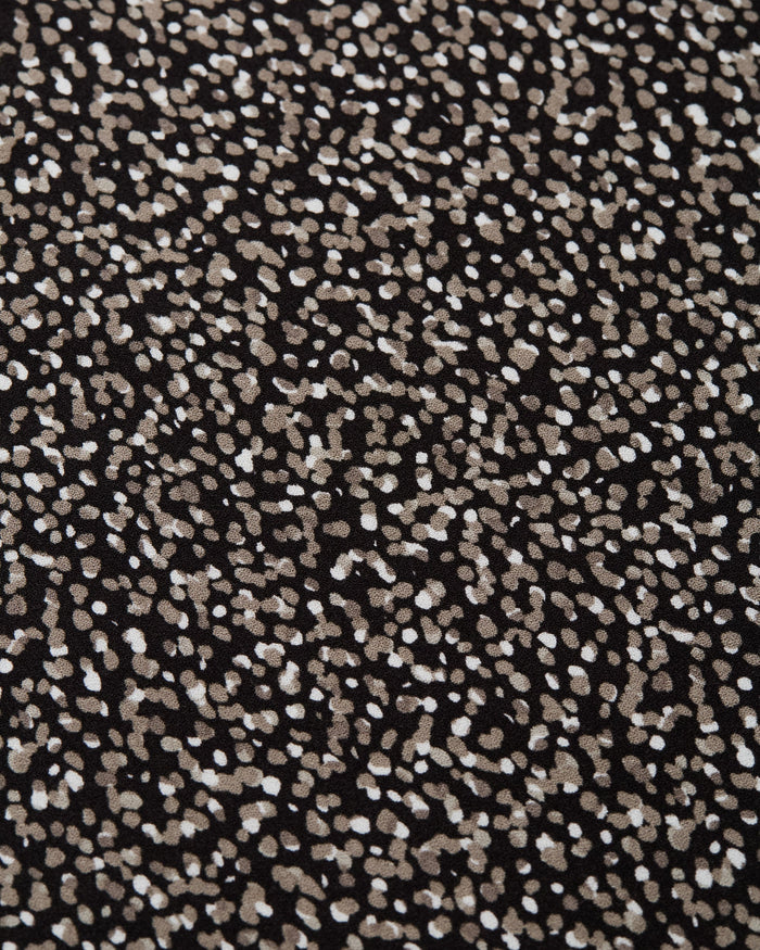 Black fabric with scattered white and beige polka dot pattern detail