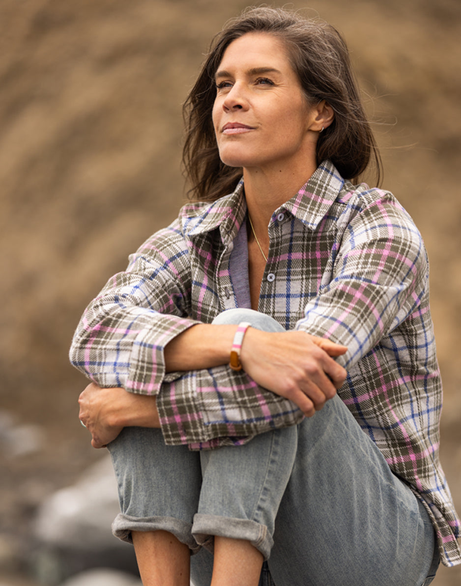Women's plaid flannel shirt in green and pink tartan, worn open over gray tee, lifestyle shot