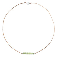 Minimalist cord necklace with green faceted stone beads centered on tan cord, silver clasp