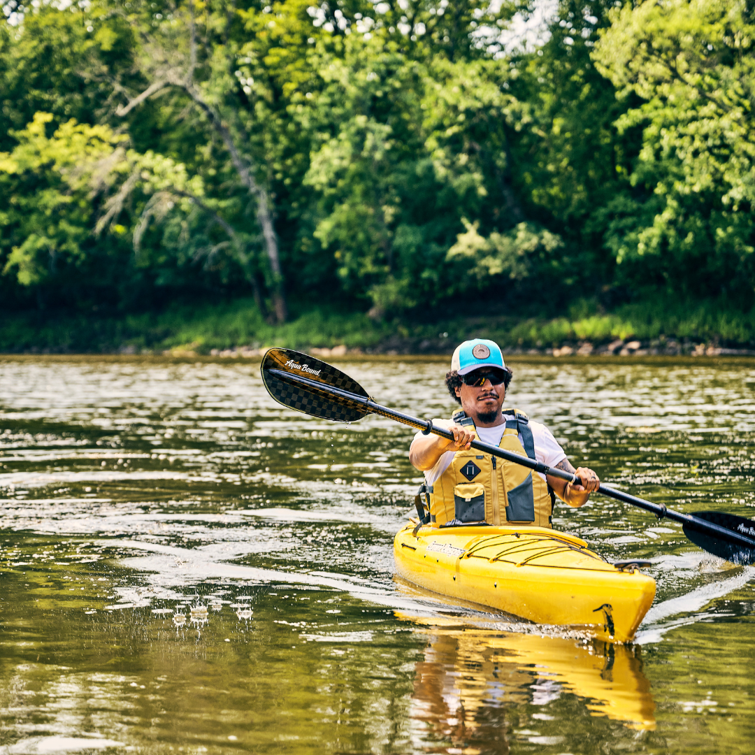 Kayaker paddling with black carbon fiber paddle on calm water