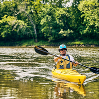 Kayaker paddling with black carbon fiber paddle on calm water