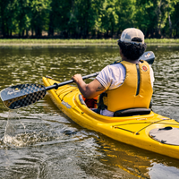 Two-piece carbon kayak paddle with checkered pattern blade being used in yellow kayak