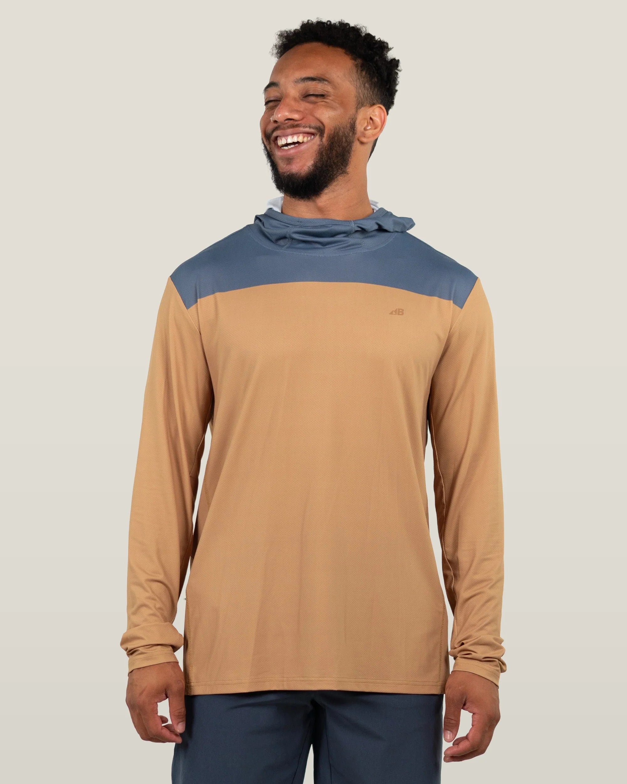 Long sleeve hooded shirt with tan body and blue shoulders worn by smiling man