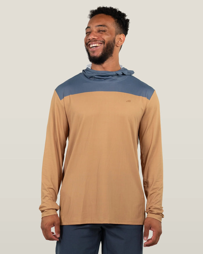 Long sleeve hooded shirt with tan body and blue shoulders worn by smiling man