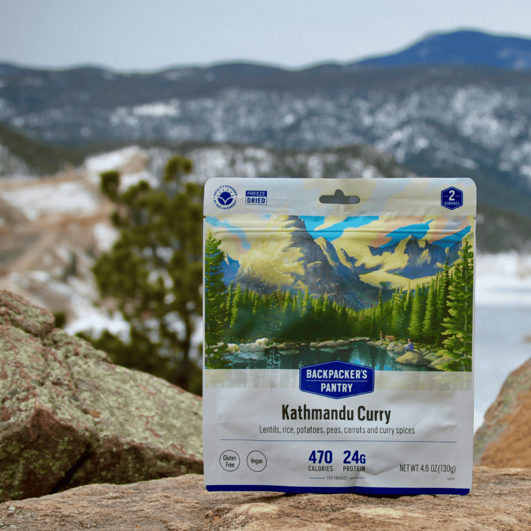 Freeze-dried meal pouch with mountain landscape artwork positioned on rocky outdoor surface