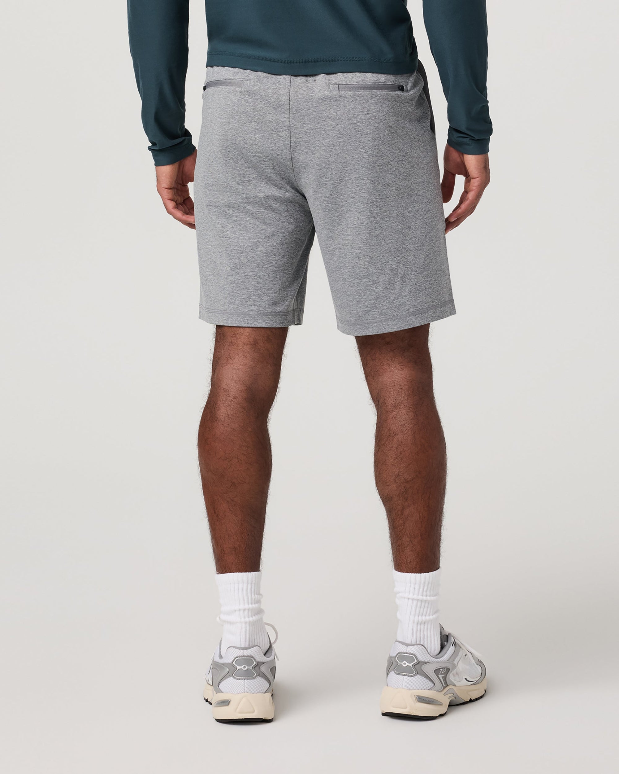 Men's grey heather performance shorts, back view, worn with teal long-sleeve and white sneakers