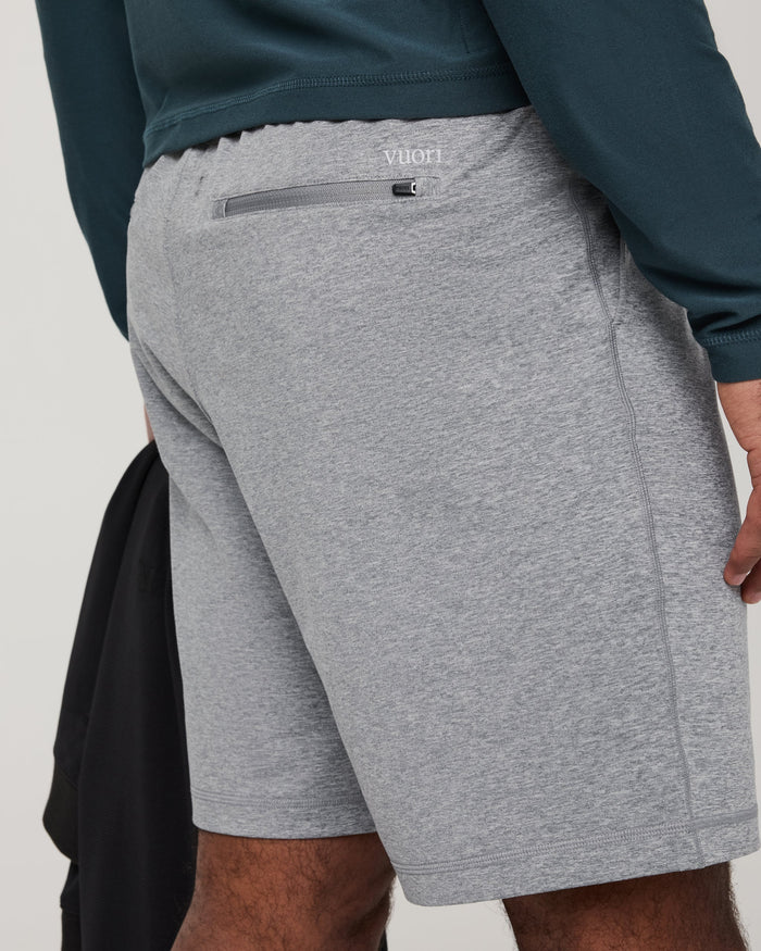 Men's athletic shorts back view showing zippered pocket and brand logo, grey heathered fabric