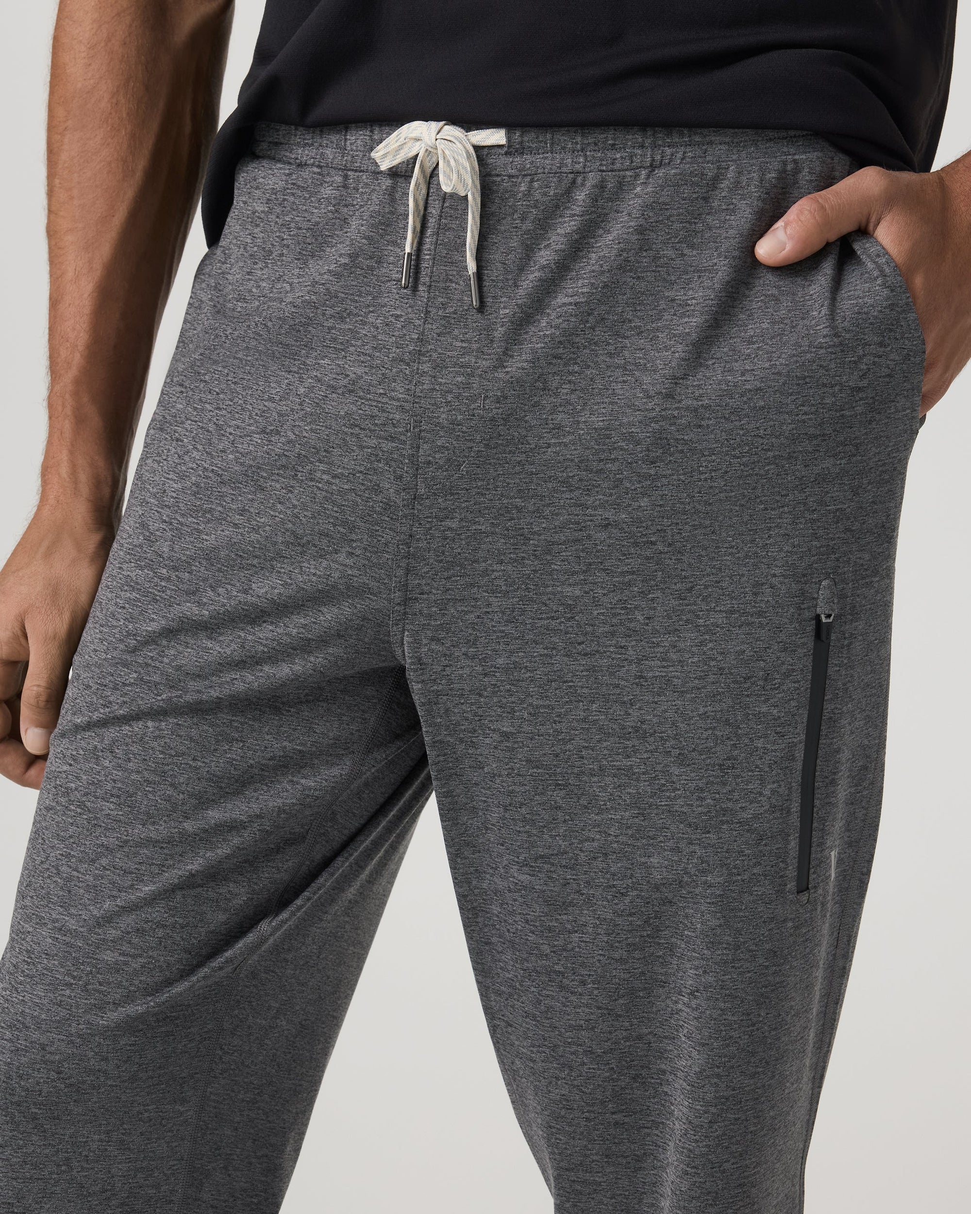 Close-up detail of men's gray jogger sweatpants showing drawstring waist and side zip pocket