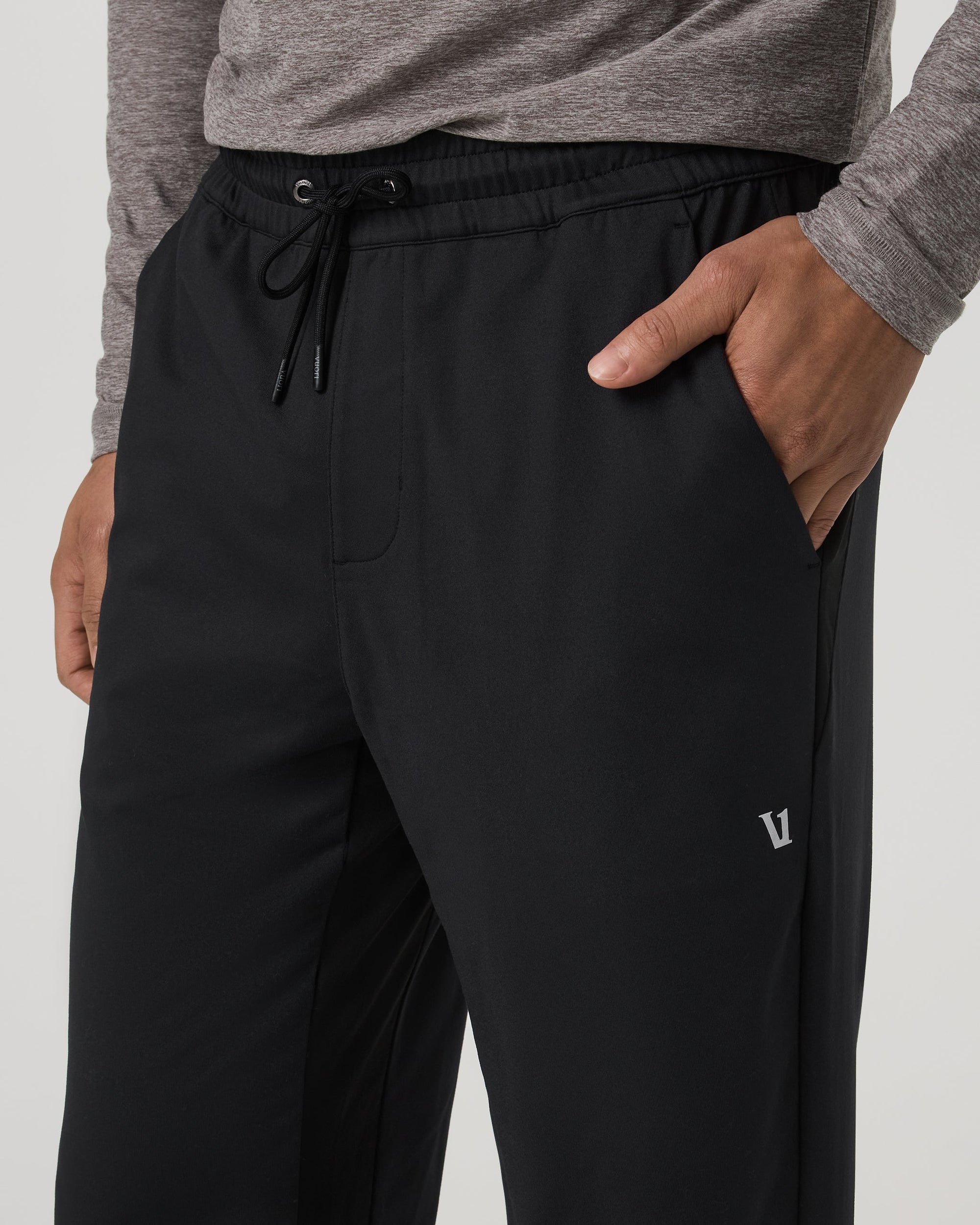 Close-up detail of black men's track pants with drawstring waist and side pocket