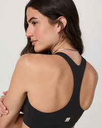 Women's high neck sports bra in black, back detail view showing racerback design on model