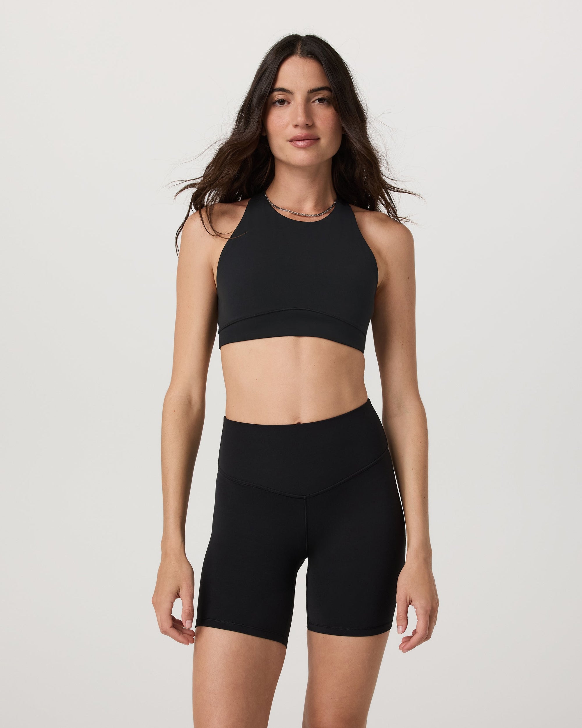 High neck sports bra in black, front view on model, sleeveless with racerback style