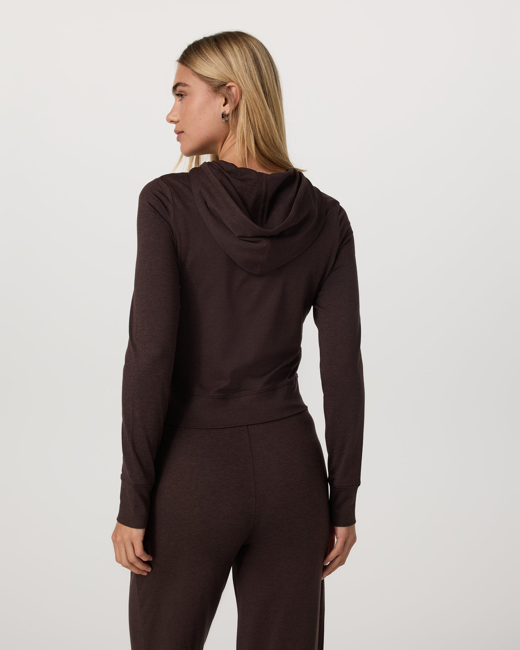 Women's cropped zip-up hoodie in dark brown, back view on model with matching pants