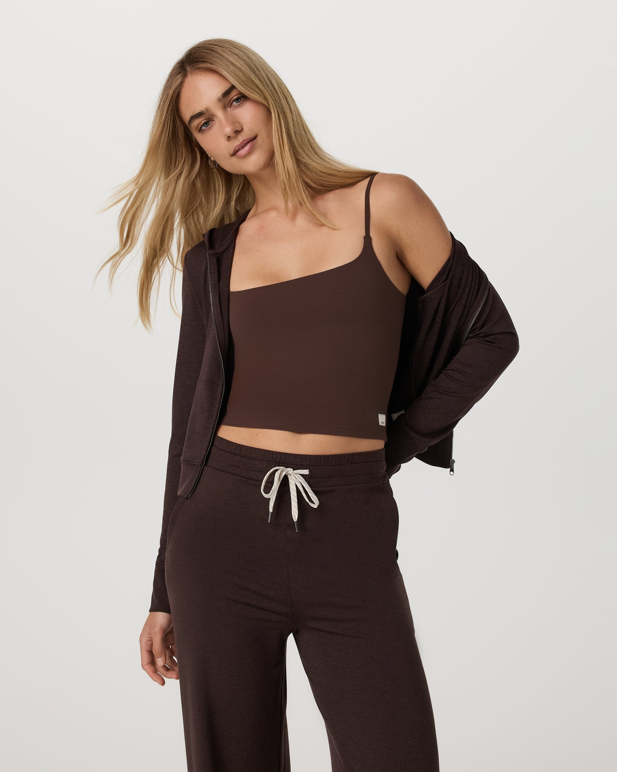 Women's mini zip-up hoodie in dark brown, worn open over matching crop top and wide-leg pants