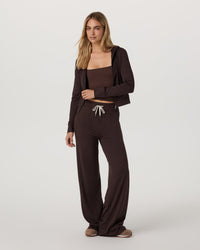 Women's cropped full-zip hoodie in dark brown, worn open over matching tube top and wide-leg pants