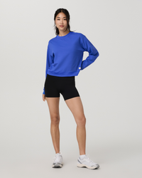 Women's cropped crew neck sweatshirt in bright blue, full-body front view on model