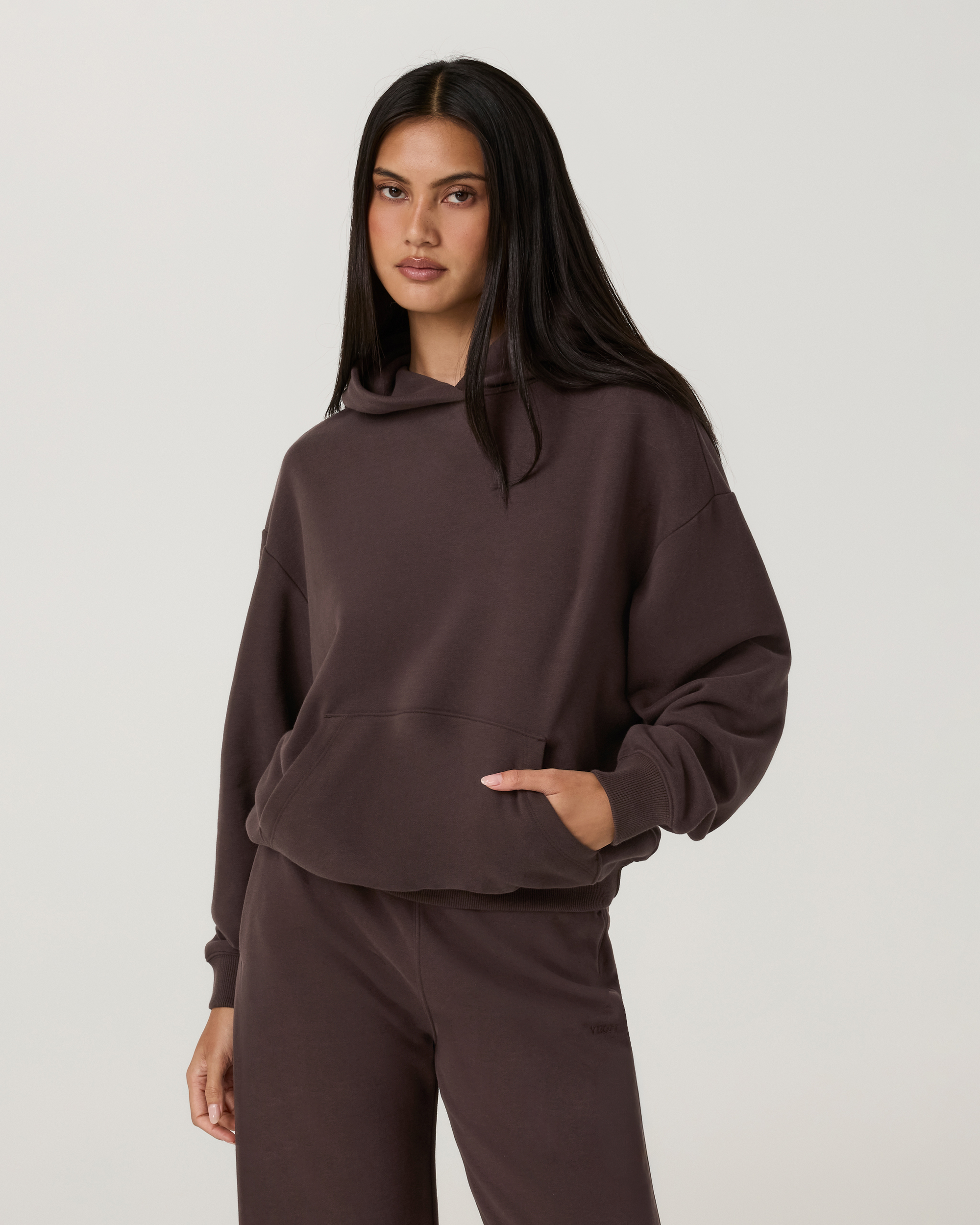 Women's oversized pullover hoodie in dark brown, front view with kangaroo pocket