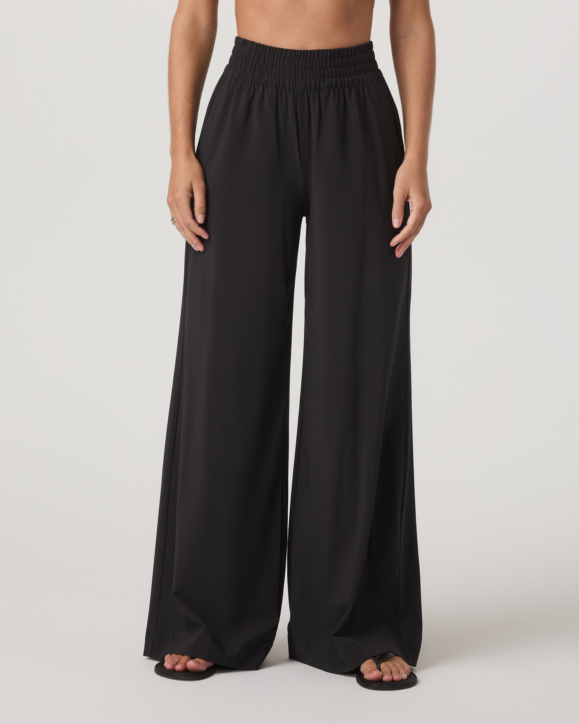 Black wide-leg pants with smocked elastic waistband, front view on model