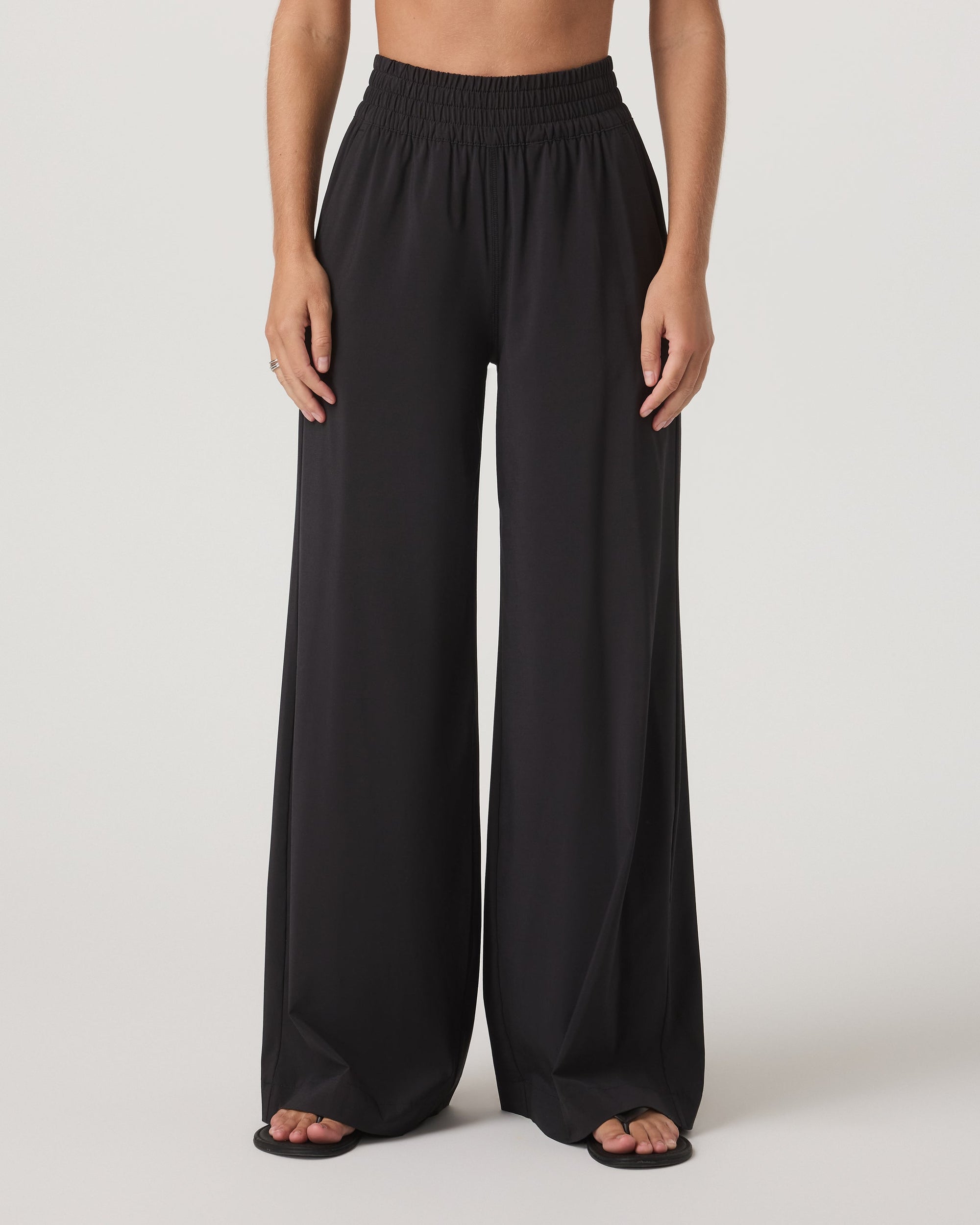 Black wide-leg pants with smocked elastic waistband, front view on model