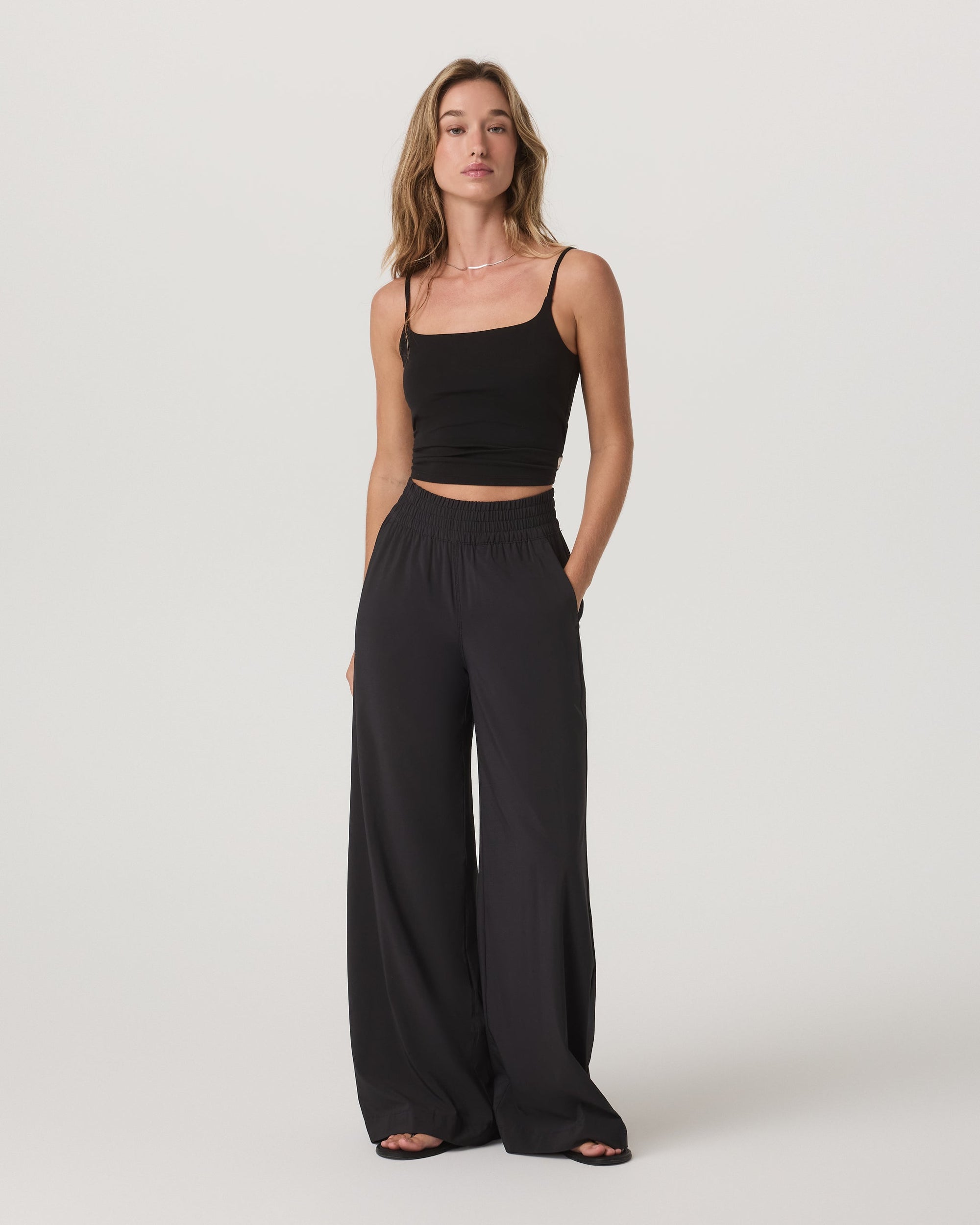 Black wide-leg flowy pants with smocked waistband, full-length front view on model