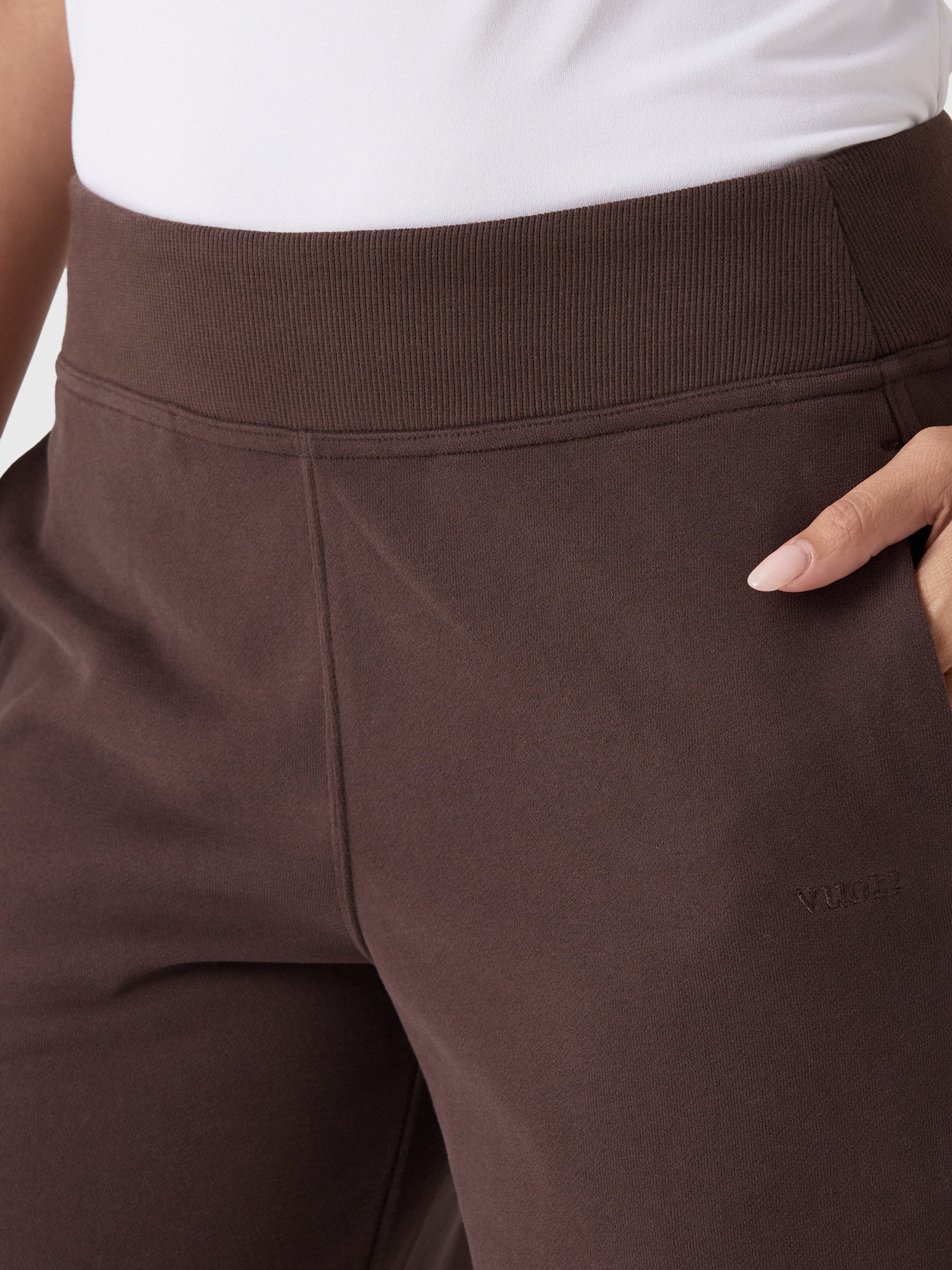 Close-up detail of dark brown wide-leg sweatpants with ribbed waistband and side pocket
