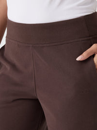 Close-up detail of dark brown wide-leg sweatpants with ribbed waistband and side pocket
