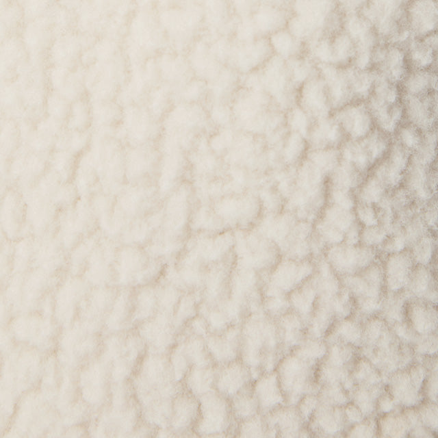 Close-up swatch of cream-colored sherpa fleece fabric with textured, curly pile surface
