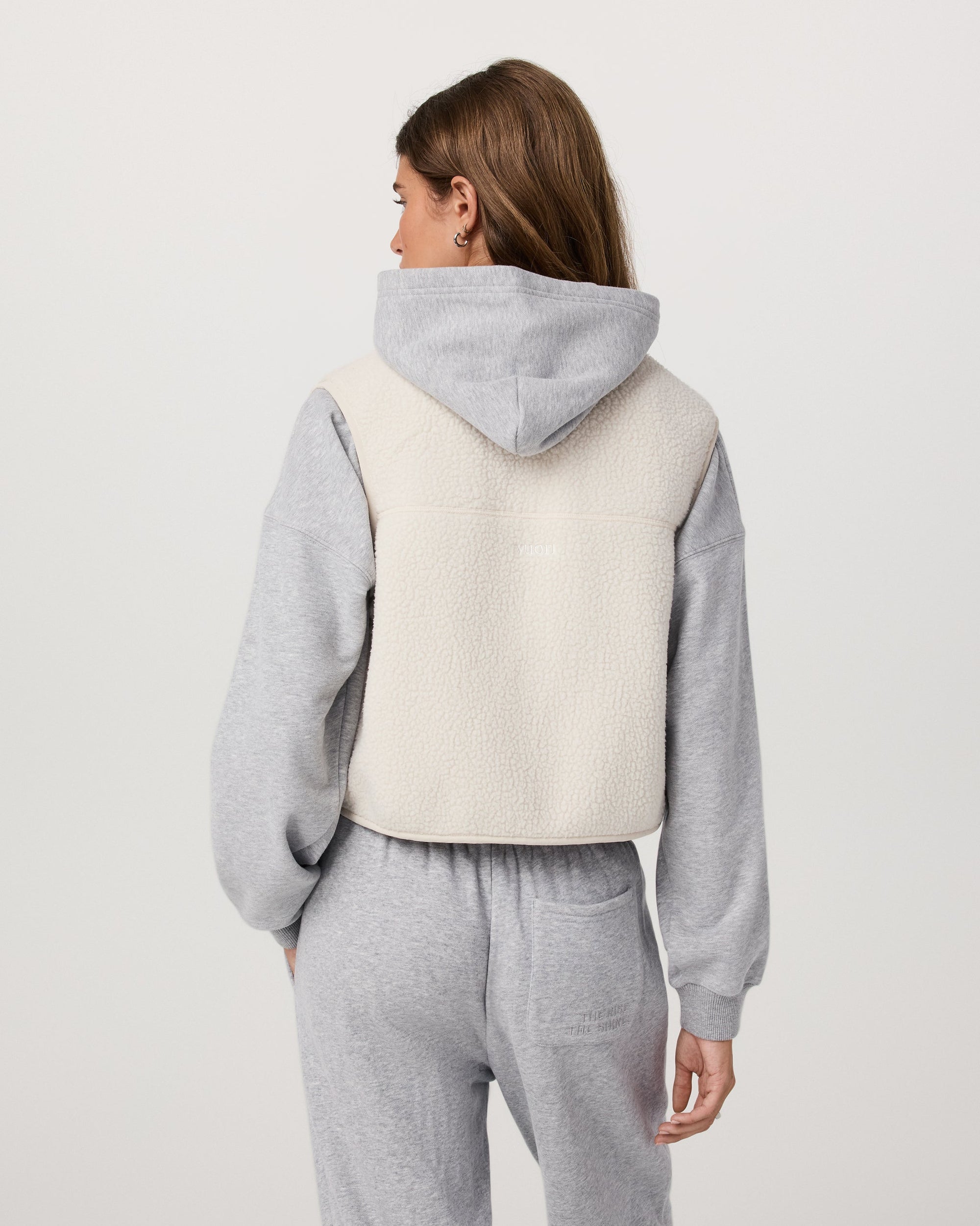 Women's sherpa fleece vest in off-white, back view, worn over grey hoodie
