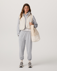 Women's cropped sherpa fleece vest with zip front, worn over grey hoodie, front view