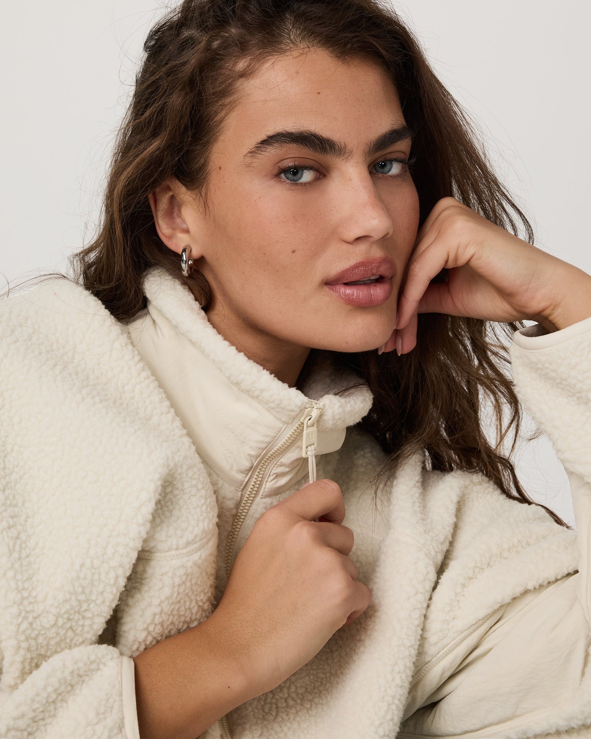 Close-up detail of cream sherpa fleece jacket with zip collar on female model