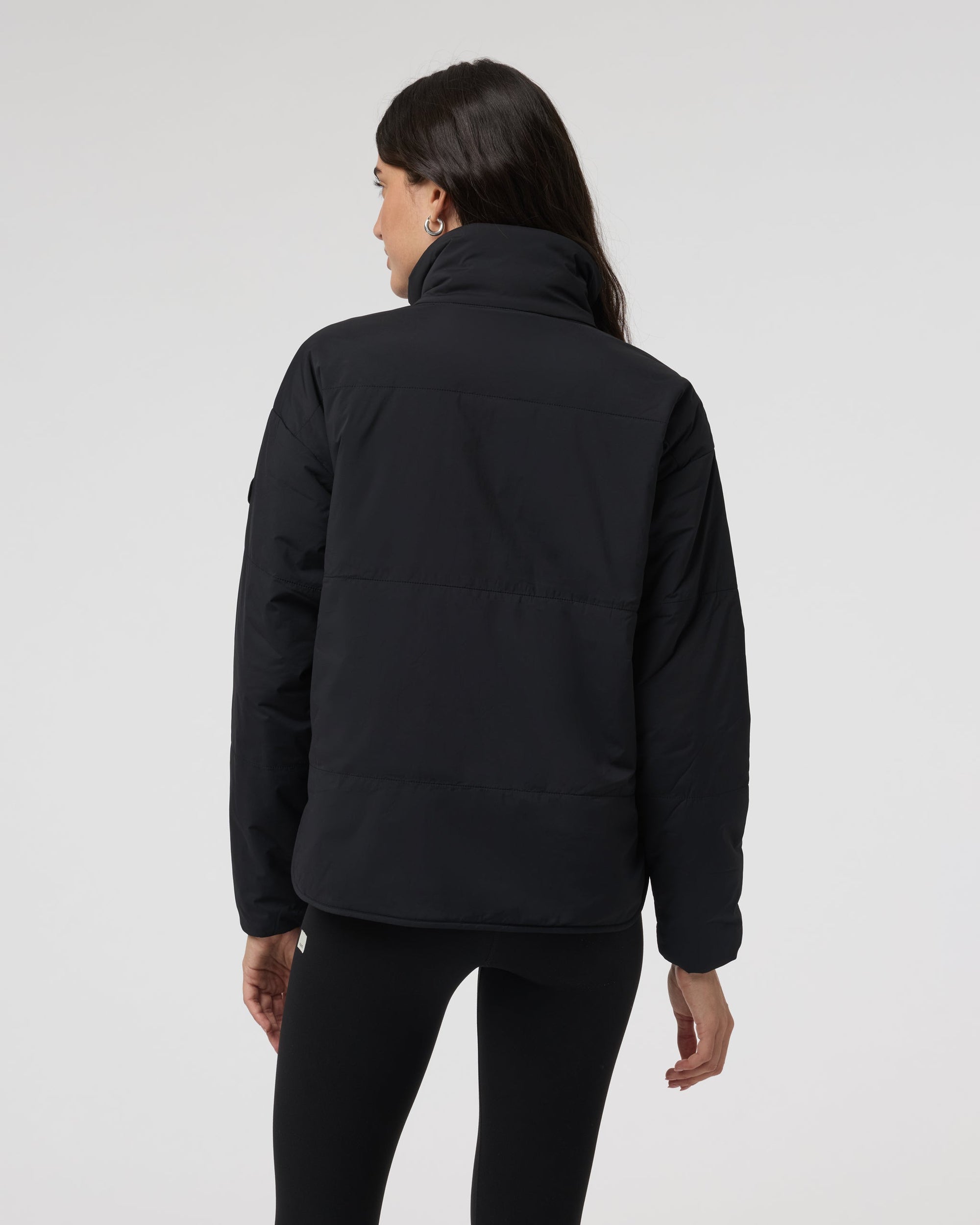 Women's black insulated puffer jacket with high collar, back view on model