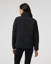 Women's black insulated puffer jacket with high collar, back view on model
