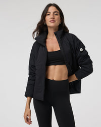 Women's black insulated puffer jacket open front view with stand collar, on model