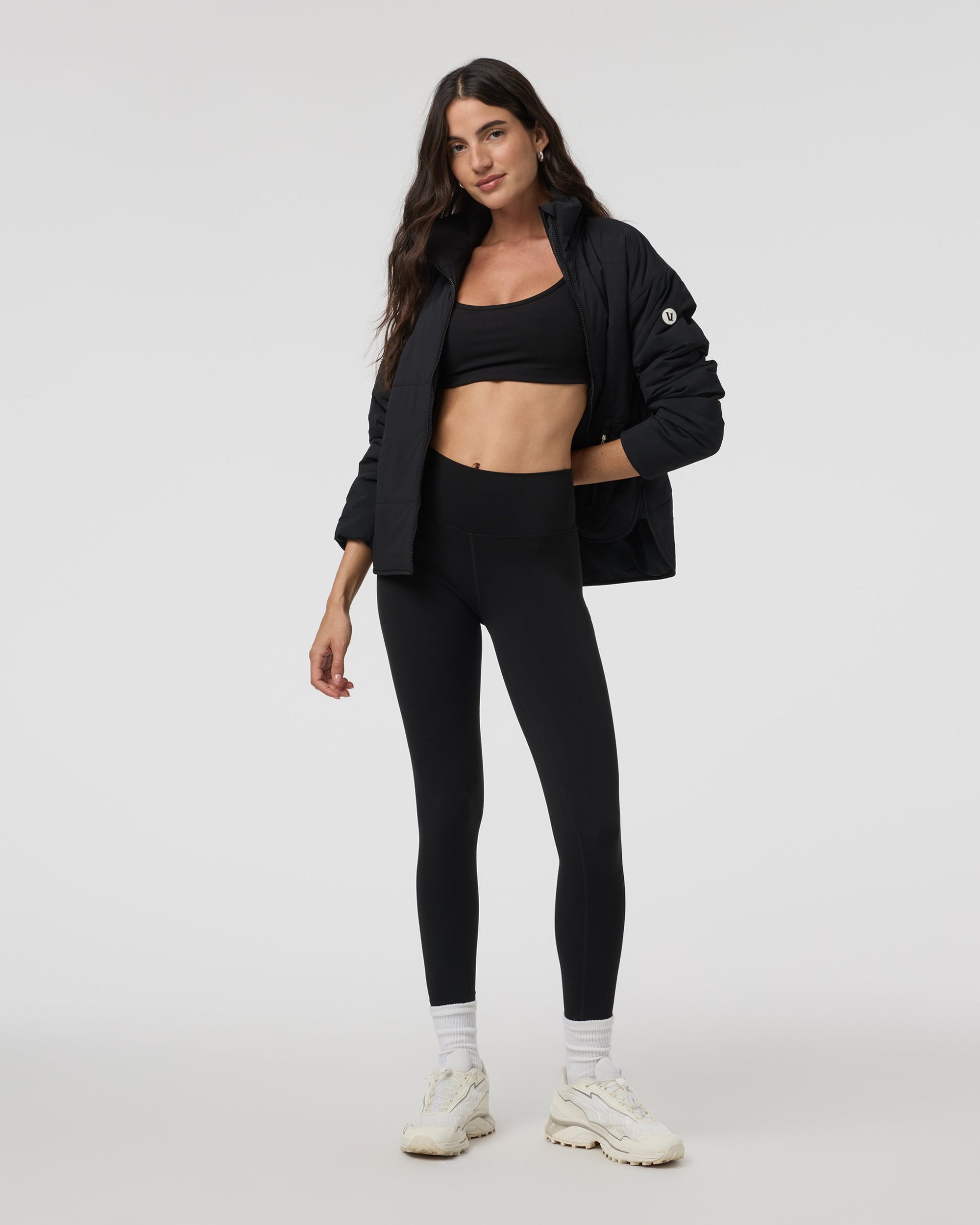 Black insulated puffer jacket open-front on model with black sports bra and leggings, front view