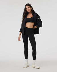 Black insulated puffer jacket open-front on model with black sports bra and leggings, front view