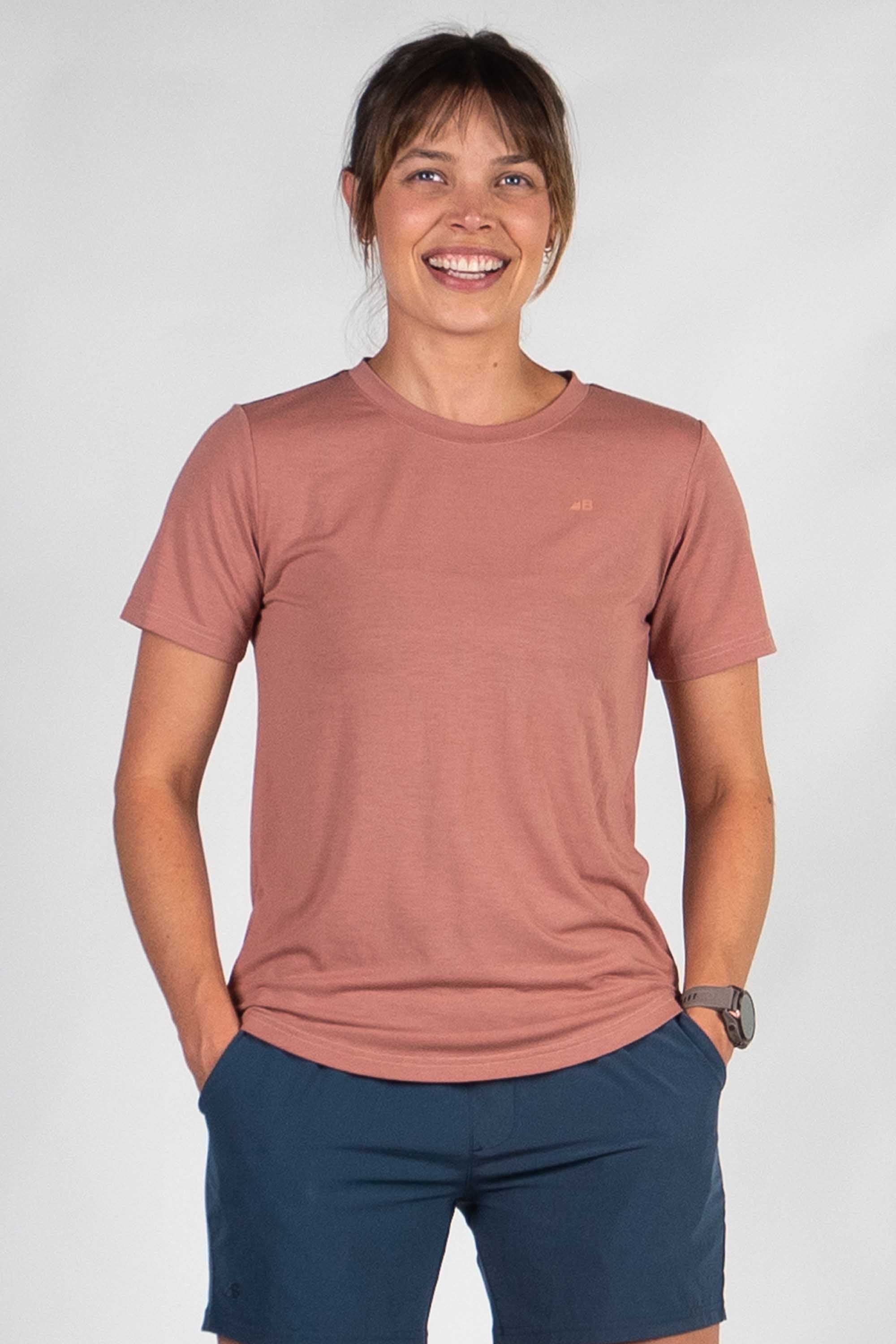 Woman wearing dusty rose short-sleeve t-shirt with navy shorts, smiling at camera