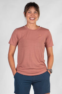 Woman wearing dusty rose short-sleeve t-shirt with navy shorts, smiling at camera