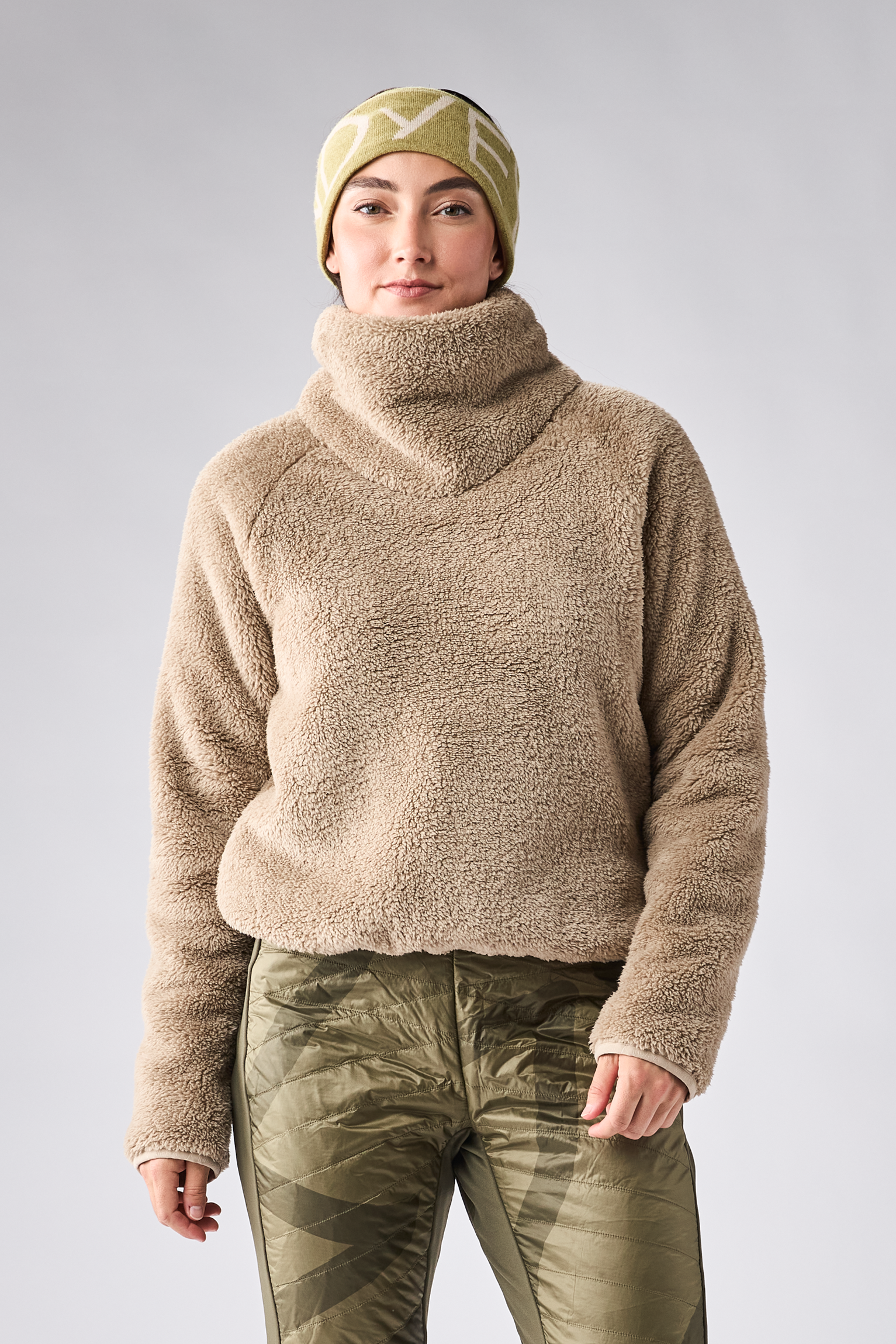 Women's sherpa fleece turtleneck pullover in warm beige, front view on model